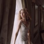 woman in white dress standing beside window